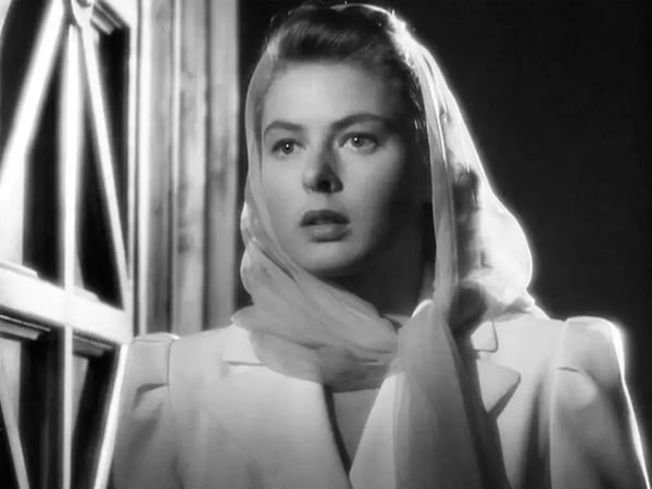 Black and white photo of woman from Casablanca wearing light scarf and light jacket staring into the distance.