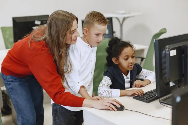 Students working on computer with their teacher.  