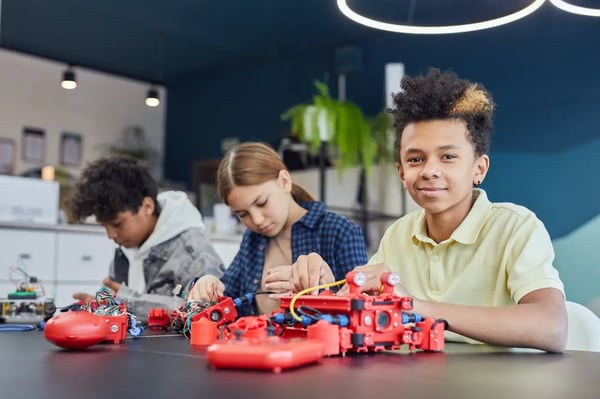 Three elementary students working on a robotics project in class.