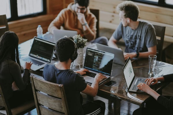 Higher ed students working on computers at table.