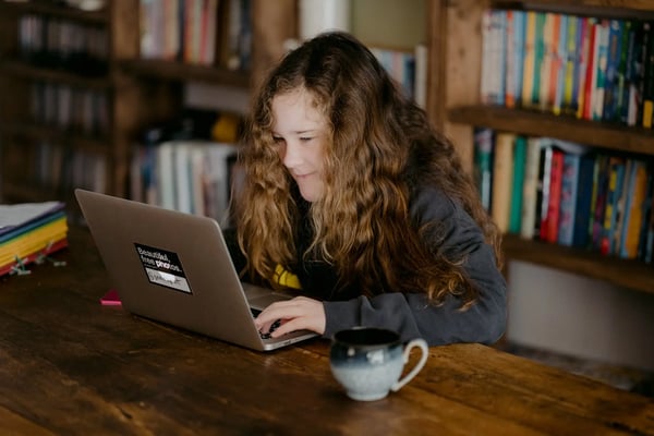 Young teen doing schoolwork on laptop.