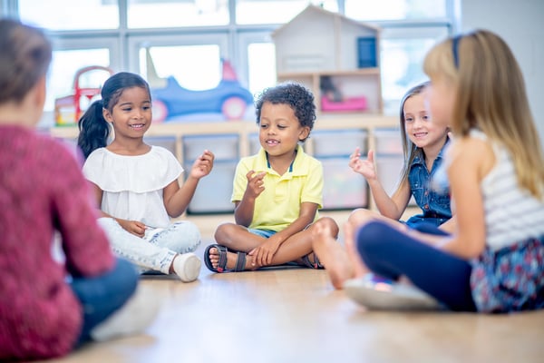 Elementary children sitting in circle, practicing SEL skills.