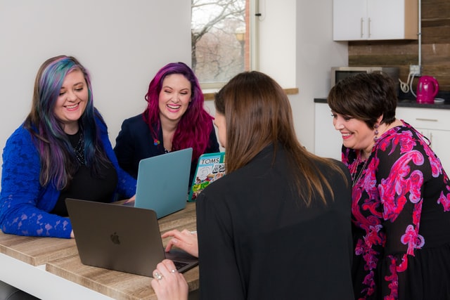 Four women looking at laptops around a table.