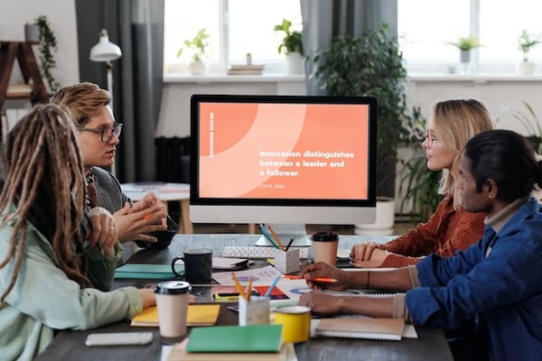 Four people gathered around a computer presentation engaged by the topic