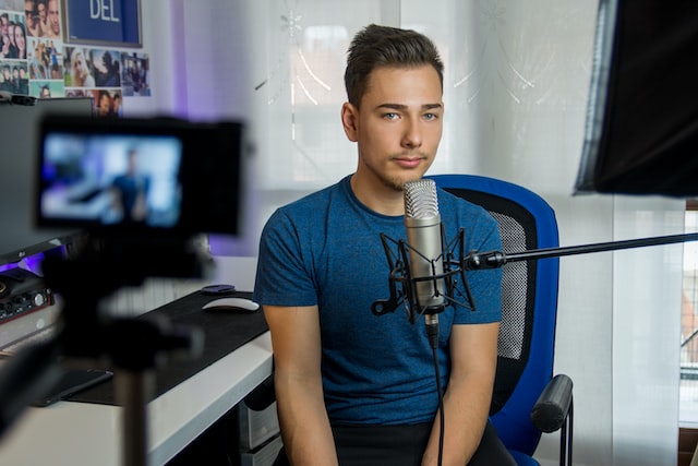 Man sitting behind a mic while filming a video