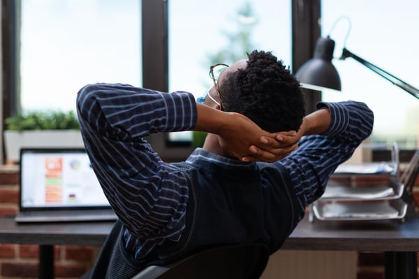 Overworked employee sitting at desk leaning back and feeling tired