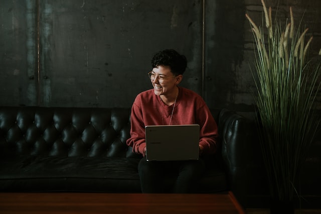 Smiling person using laptop to create YouTube videos