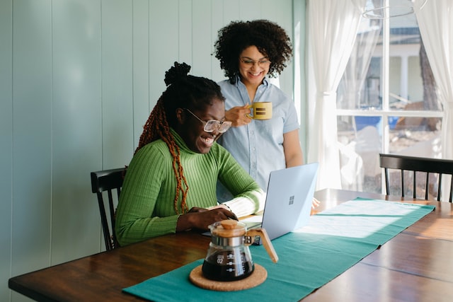 Two women watching training videos while smiling and sitting at table