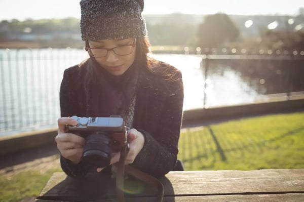 A brunette, female photographer with a winter hat taking a texture photo of wood.