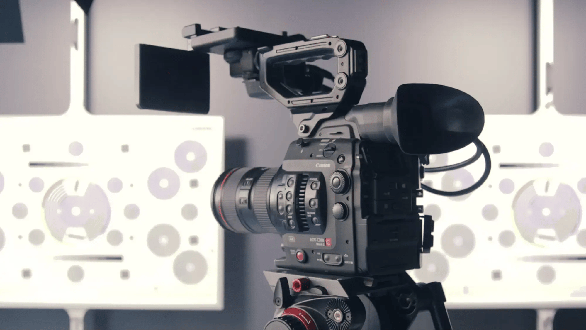 A stills lens and camera sit atop a tripod positioned at a series of markings in the background.