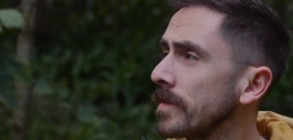 Close-up of man with facial hair outside looking into the distance with soft grain texture and grain overlay.